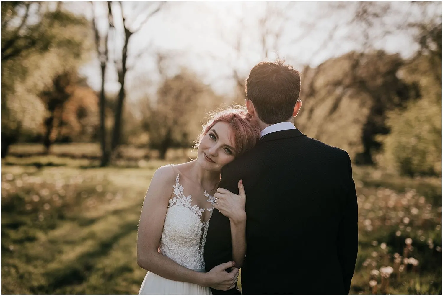 Bride resting her head on the groom's shoulder in golden-hour light
